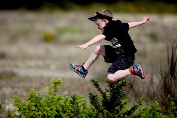 Channel your inner child. Boy Running Through a Field Jumping and Having Fun